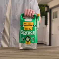 Mężczyzna trzyma butelkę środka "Spruce" - orkan na chwasty. Skutecznie zwalcza chwasty, trawy i mech.