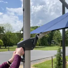 Ręce obracają korbę mechanizmu parasola ogrodowego.