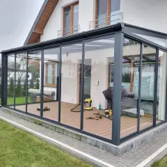 Nowoczesna szklana pergola z ruchomym dachem nad tarasem.
