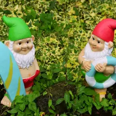 Dwa krasnale ogrodowe, jeden z deską surfingową, drugi z kołem ratunkowym. Idealne do ogrodu, czym pomalować krasnale ogrodowe?