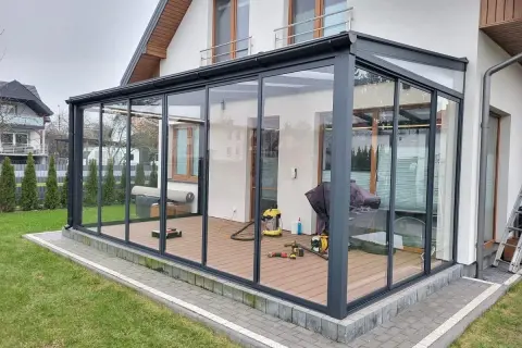 Nowoczesna szklana pergola z ruchomym dachem nad tarasem.