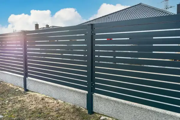 Nowoczesne ogrodzenie z poziomymi deskami, co zamiast podmurówki pod ogrodzenie? Betonowy cokół stanowi estetyczne i trwałe rozwiązanie.