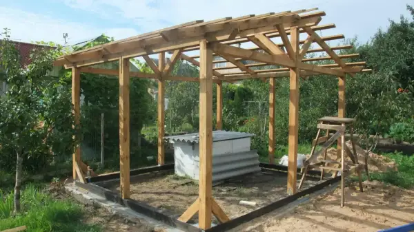 Drewniana konstrukcja altany w trakcie budowy, z widocznym fundamentem i dachem.